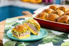 a plate with a sandwich on it next to a casserole dish full of muffins