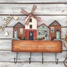 a wooden sign that says down town, get cozy with houses and windmills on it