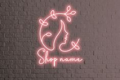 a neon sign on the side of a brick wall that says, shop name