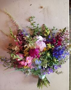 a vase filled with lots of different types of flowers on top of a table next to a wall