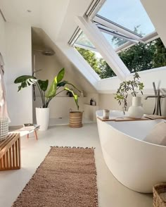 a large white bathtub sitting under a skylight next to a plant in a vase