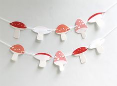 a string of paper mushrooms is hanging on a white wall with red and white polka dots