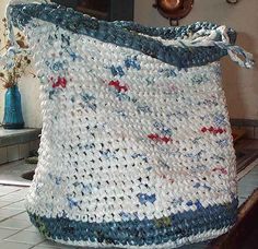 a large white bag sitting on top of a wooden table next to a blue vase