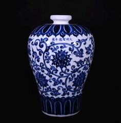 a blue and white vase sitting on top of a black table next to a wall