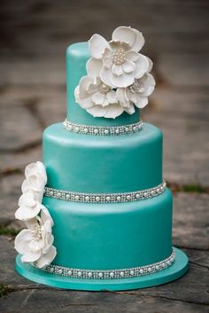 a three tiered blue cake with white flowers on top