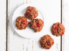 three cookies on a white plate with strawberries in the middle next to one cookie