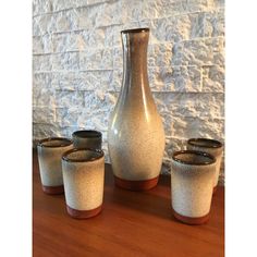 four small vases sitting on top of a wooden table