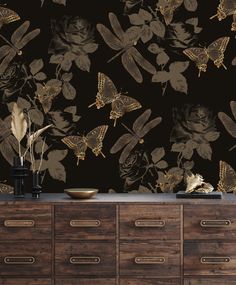 the wallpaper is black with gold butterflies and flowers on it's sideboard