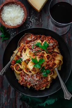 pasta with meat sauce and parmesan cheese in a black bowl on a wooden table