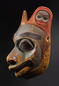 an african mask is shown against a black background and has red accents on the face