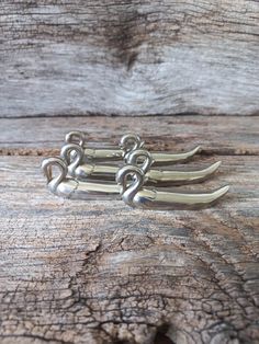 three silver hair clips sitting on top of a wooden table