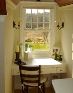 a desk and chair in front of a window with a view of the countryside outside