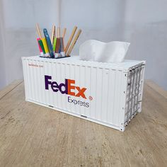 a white container that has some pens and pencils in it on a wooden table