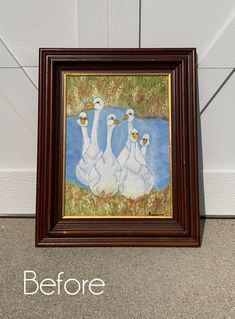 two white swans sitting in front of a painting on the wall next to a door