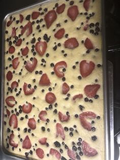 an uncooked cake with strawberries and blueberries on it in a pan