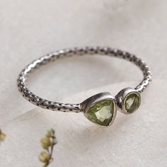 India's Bhavya Jain puts her expertise and talent into practice to create this splendid accessory for those with a harmonious and lucky soul. A sterling silver structure accented with dots forms this band ring, whose front showcases natural peridot jewels shining with green light. Green Sterling Silver Hammered Jewelry, Green Hammered Sterling Silver Jewelry, Adjustable Peridot Jewelry For Anniversary, Nickel-free Silver Peridot Jewelry, Spring Green, Green Light, Band Ring, Light Green, Band Rings