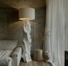 a white couch sitting next to a lamp on top of a wooden table in a living room