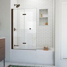 a bathroom with white tiles and a brown wooden cabinet next to the bathtub is shown