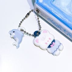 two keychains are sitting next to each other on a white table with a blue box in the background