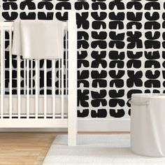 a white crib in front of a black and white wallpaper with an abstract design