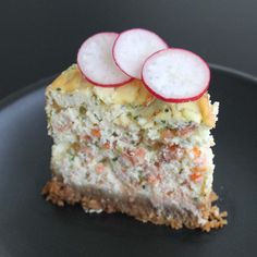 a piece of cake with radishes on top is sitting on a black plate