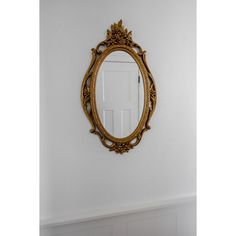 an ornate gold framed mirror hangs on the wall next to a white door in a room