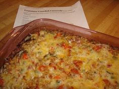 a casserole dish with cheese and vegetables in it sitting on a wooden table