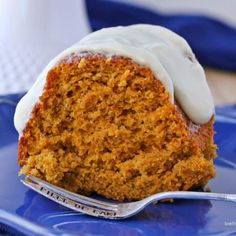 a piece of carrot cake on a blue plate with a white icing drizzle