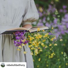 a woman is holding an open book with flowers in her lap and wearing a dress