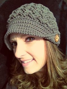 a smiling woman wearing a crocheted hat with buttons on it's brim