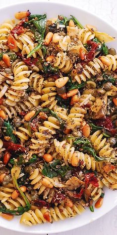 a white bowl filled with pasta and spinach