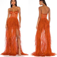 a woman wearing an orange dress with feathers on the skirt and high slited heels