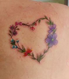 a heart shaped flower tattoo on the back of a woman's upper back shoulder