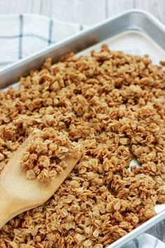 a pan filled with granola next to a wooden spoon