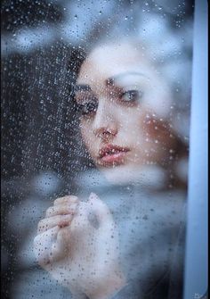 a woman is looking out the window in the rain