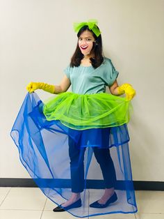 a woman in a green dress and yellow gloves is holding a blue netted skirt