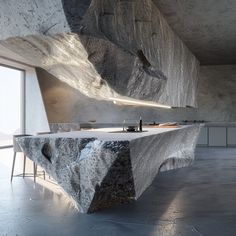 an unusual kitchen counter made out of rock and concrete, with a sink in the middle