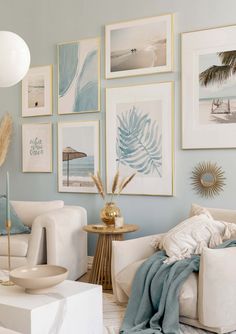 a living room filled with white furniture and pictures on the wall above it's coffee table