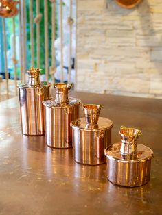 four copper canisters sitting on top of a table