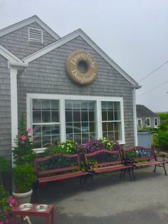 the outside of a restaurant with benches and potted plants in front of it on a cloudy day