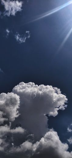 the airplane is flying high in the blue sky with white clouds and bright sun behind it