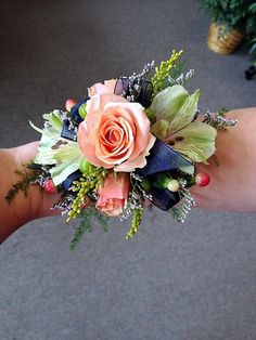 a person's hand holding a bouquet of flowers and greenery on the wrist