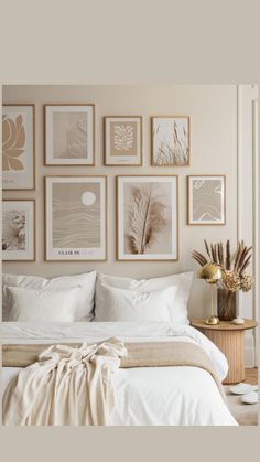 a bedroom with white bedding and pictures on the wall