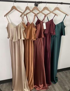 four dresses hanging on a rack in front of a wall