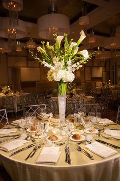 a vase filled with white flowers sitting on top of a table covered in plates and napkins