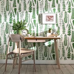 a desk and chair in front of a wallpapered with green leaves on it