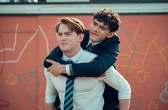 two young men hugging each other in front of graffiti