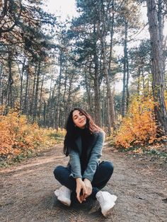 a woman kneeling down in the middle of a forest with her hands on her knees