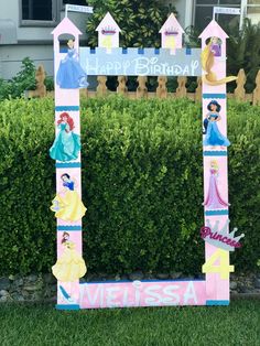 a birthday sign with princesses on it in front of a hedge and shrubbery