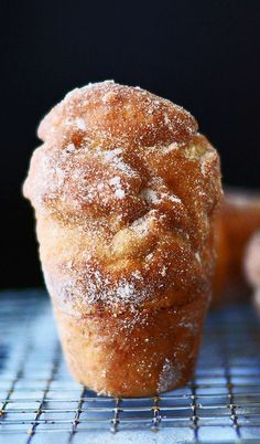 there is a powdered sugar muffin on the cooling rack with other muffins in the background